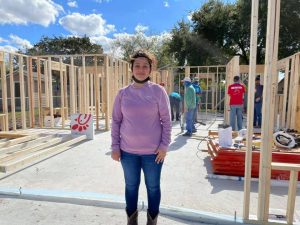 Maressa standing in front of the walls of her home after they were built at a Help Build Hope event in Texas